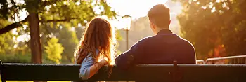 Young couple sitting on a park bench in the Burggarten